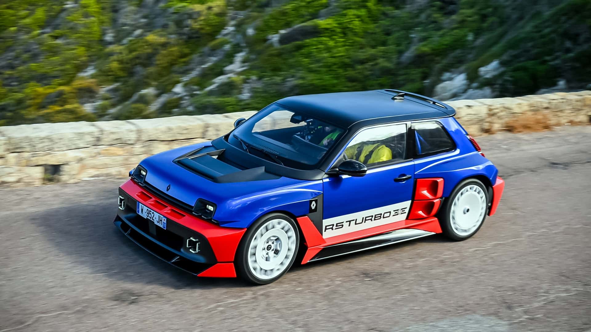 Blå og rød sportsvogn kører på naturskøn vej