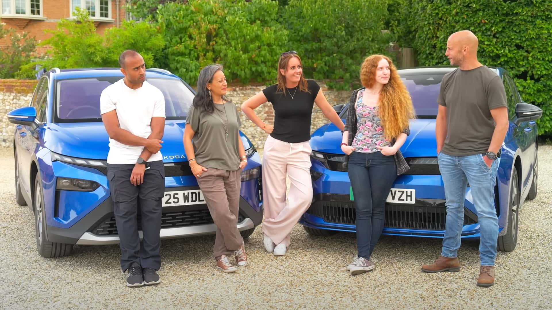 Gruppe af mennesker, der står foran to blå elektriske biler