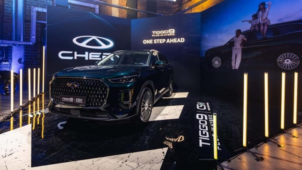 Chery Tiggo 9 plug-in hybrid bil på en udstillingsscene med oplyst baggrund