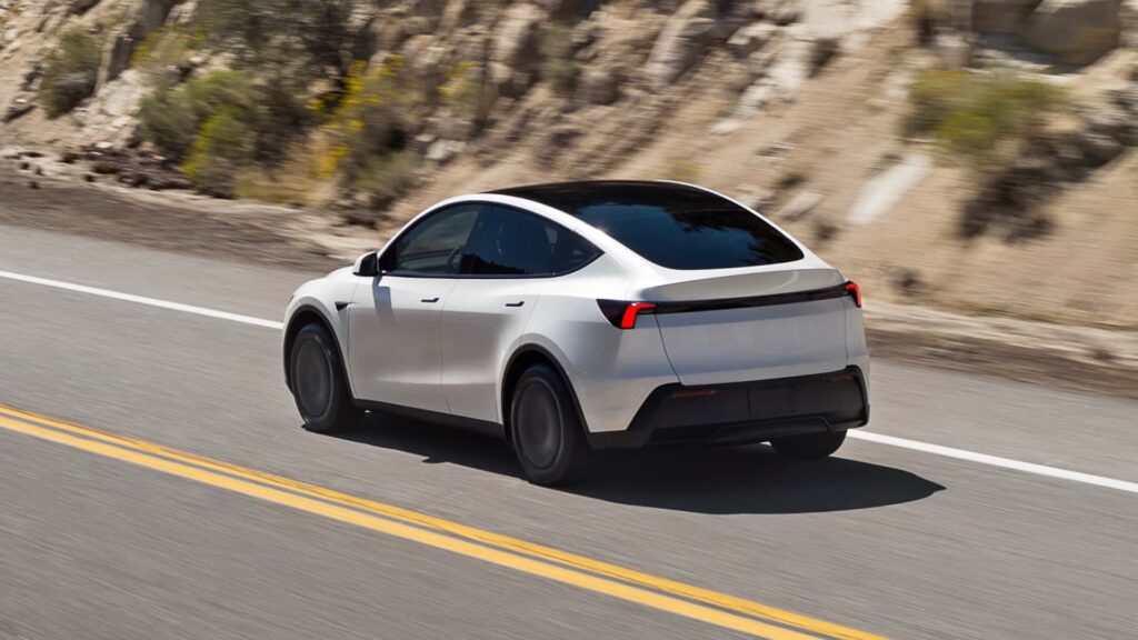 Hvid Tesla elbil kører langs en vej i naturskønne omgivelser