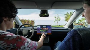 To personer sidder i en Tesla og spiller et spil på bilens touchskærm