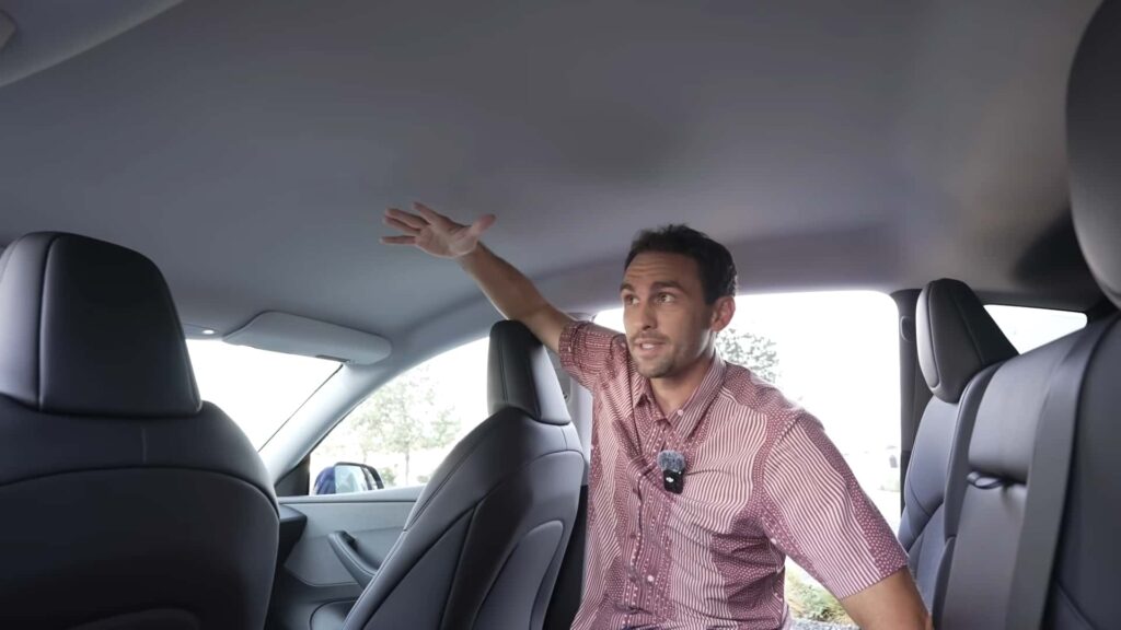 Mand demonstrerer rummelig kabine i en Tesla elbil