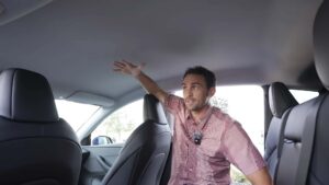 Mand demonstrerer rummelig kabine i en Tesla elbil