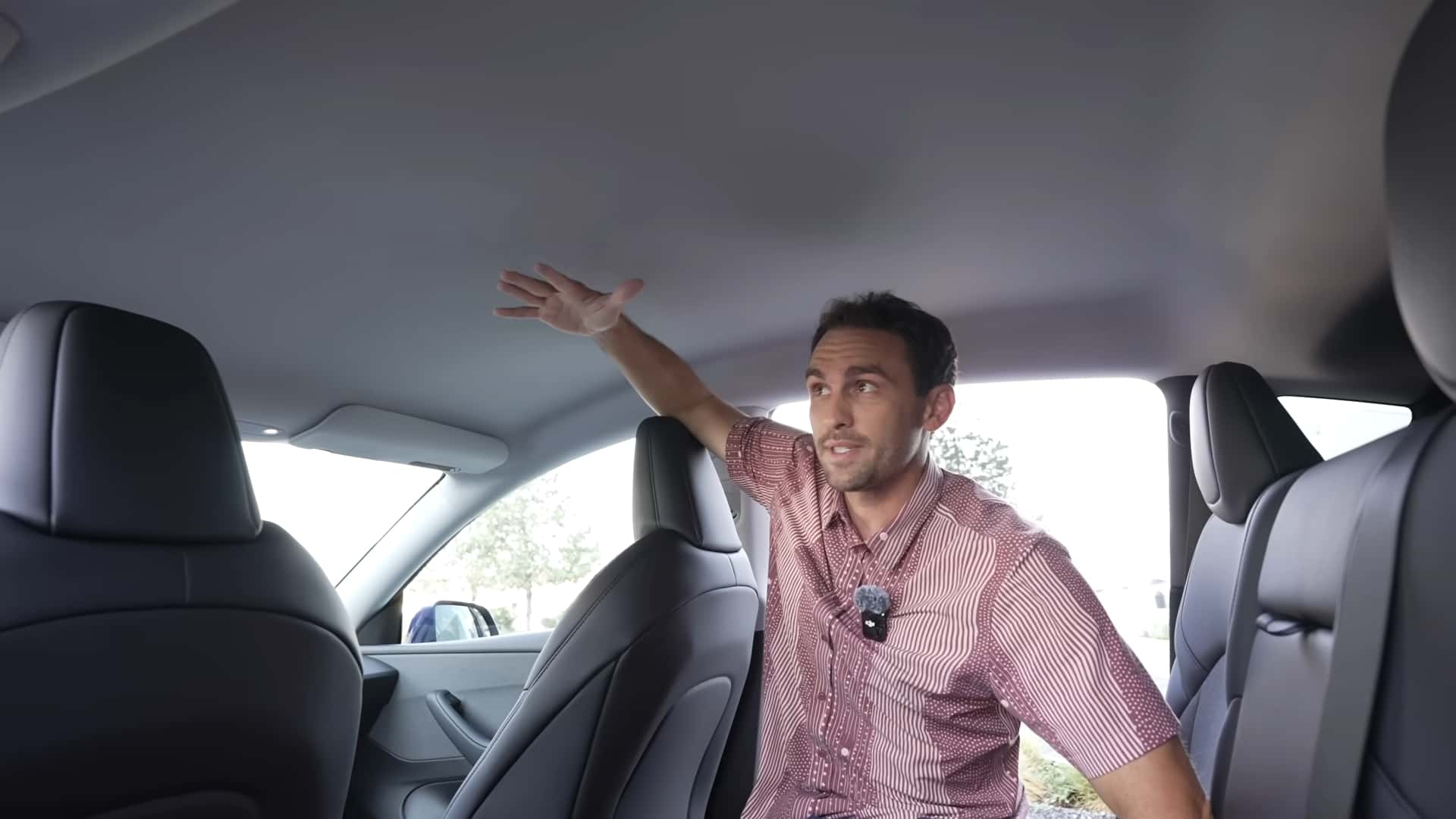 Mand demonstrerer rummelig kabine i en Tesla elbil