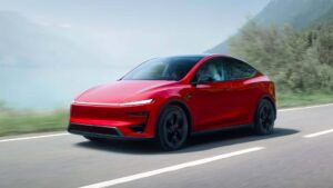 Rød Tesla elbil kører på en naturskøn vej