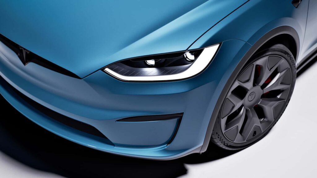 Close-up af forlygten og hjulet på en Tesla i en blå farve.