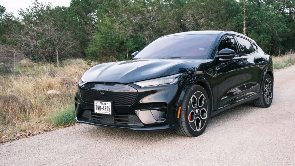 Sort elektrisk sportsvogn på en landevej omgivet af træer