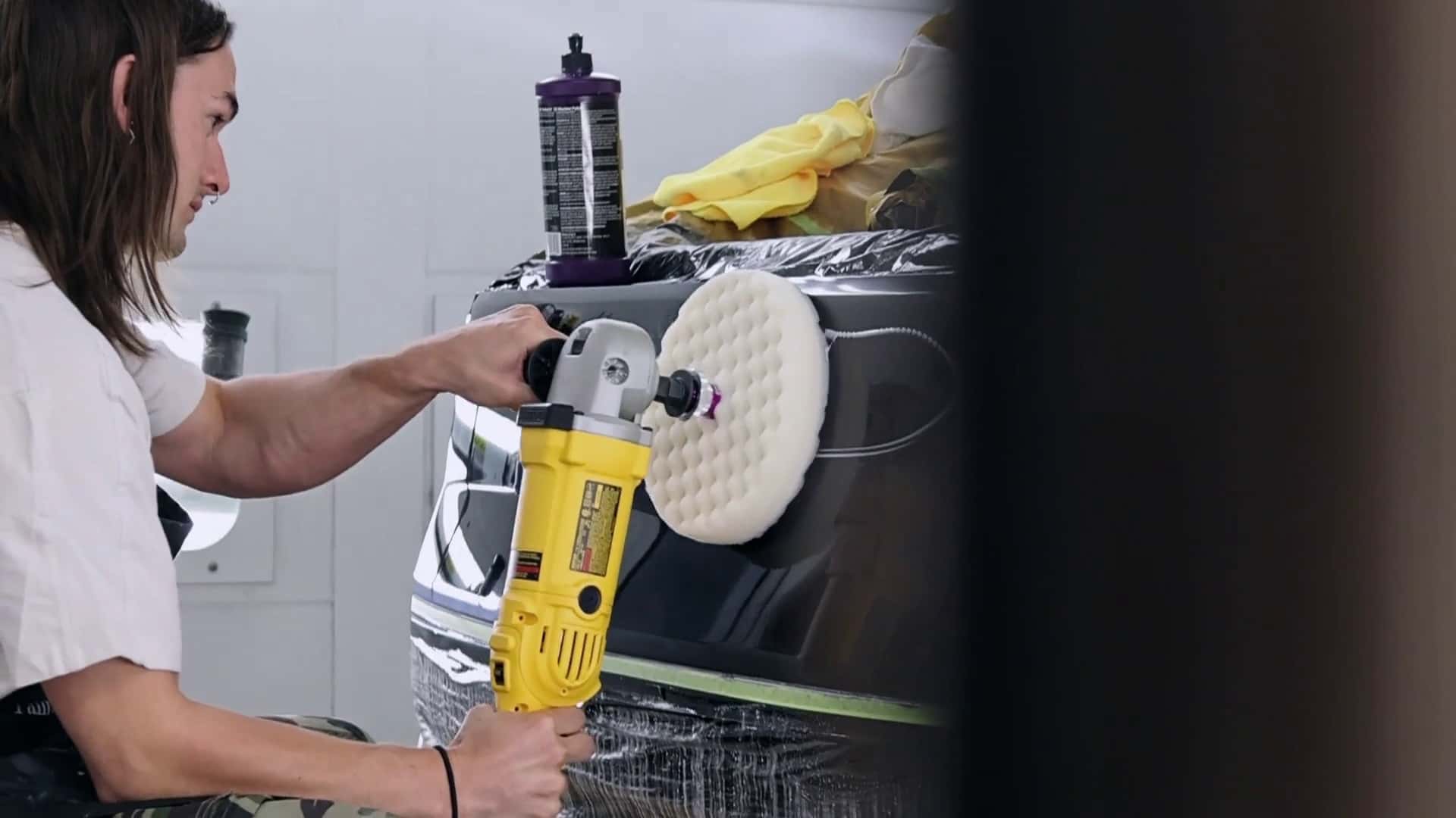 Person polerer Tesla-bil med elektrisk værktøj i værksted