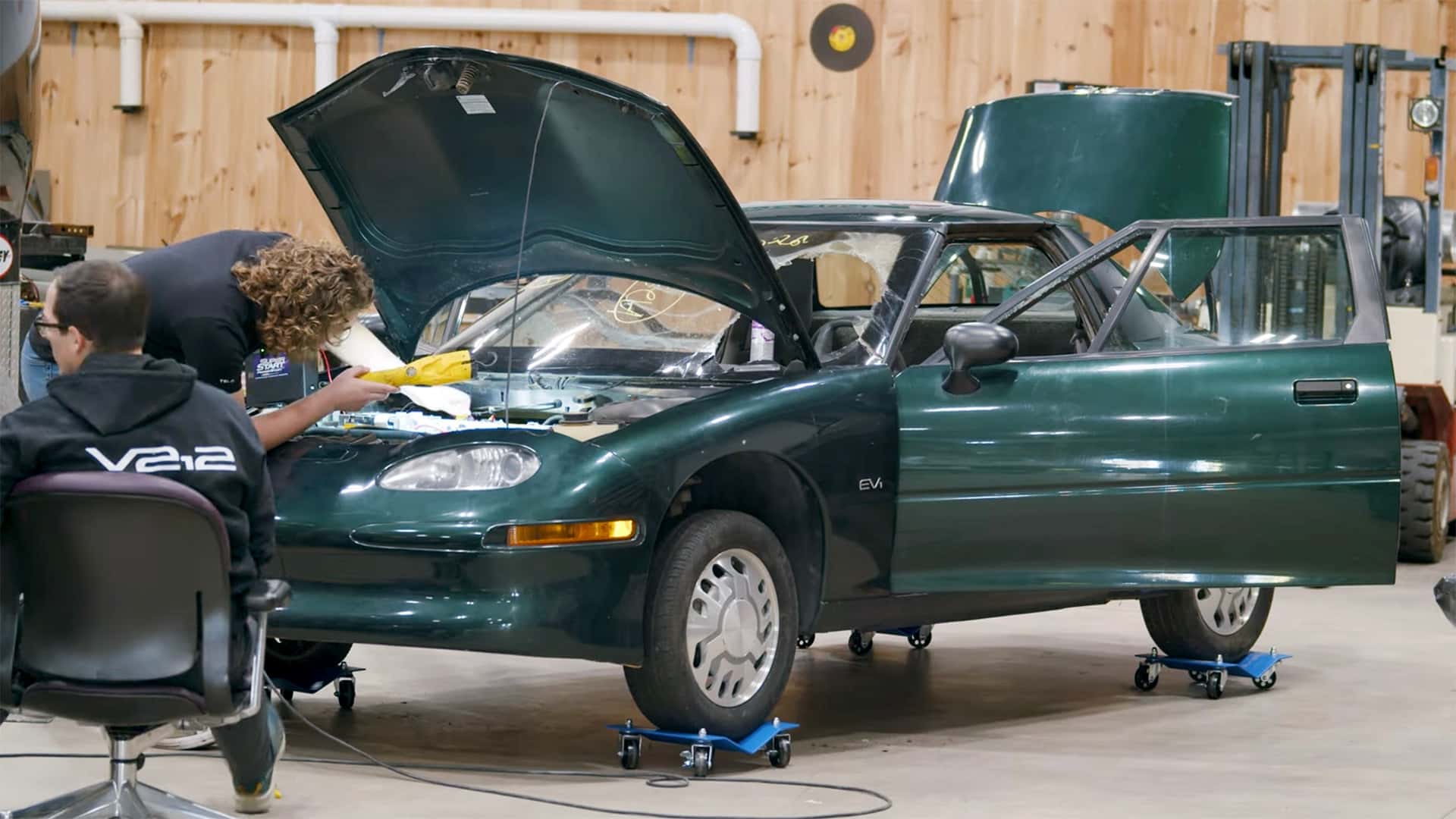 To personer arbejder på en elektrisk bil i en garage.