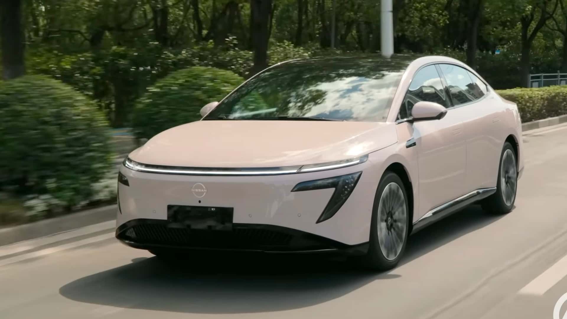 Elektrisk bil kører på vejen omgivet af grønne træer, moderne design og avanceret teknologi.