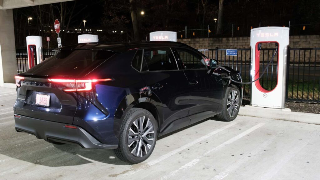 Elektrisk bil oplader ved Tesla Supercharger station om natten