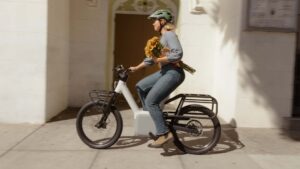 Kvinde cykler på elcykel med blomster i hånden