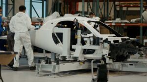 Ingeniører arbejder på samlingen af en Tesla bilramme i en produktionsfacilitet