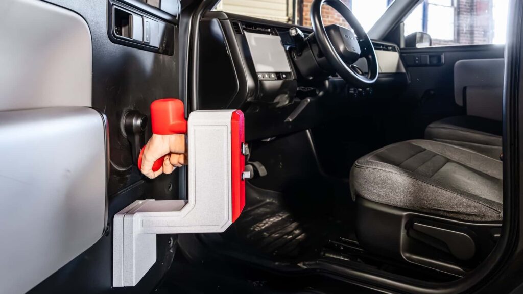 Hånd der holder en rød ladestik i en Tesla bilinteriør