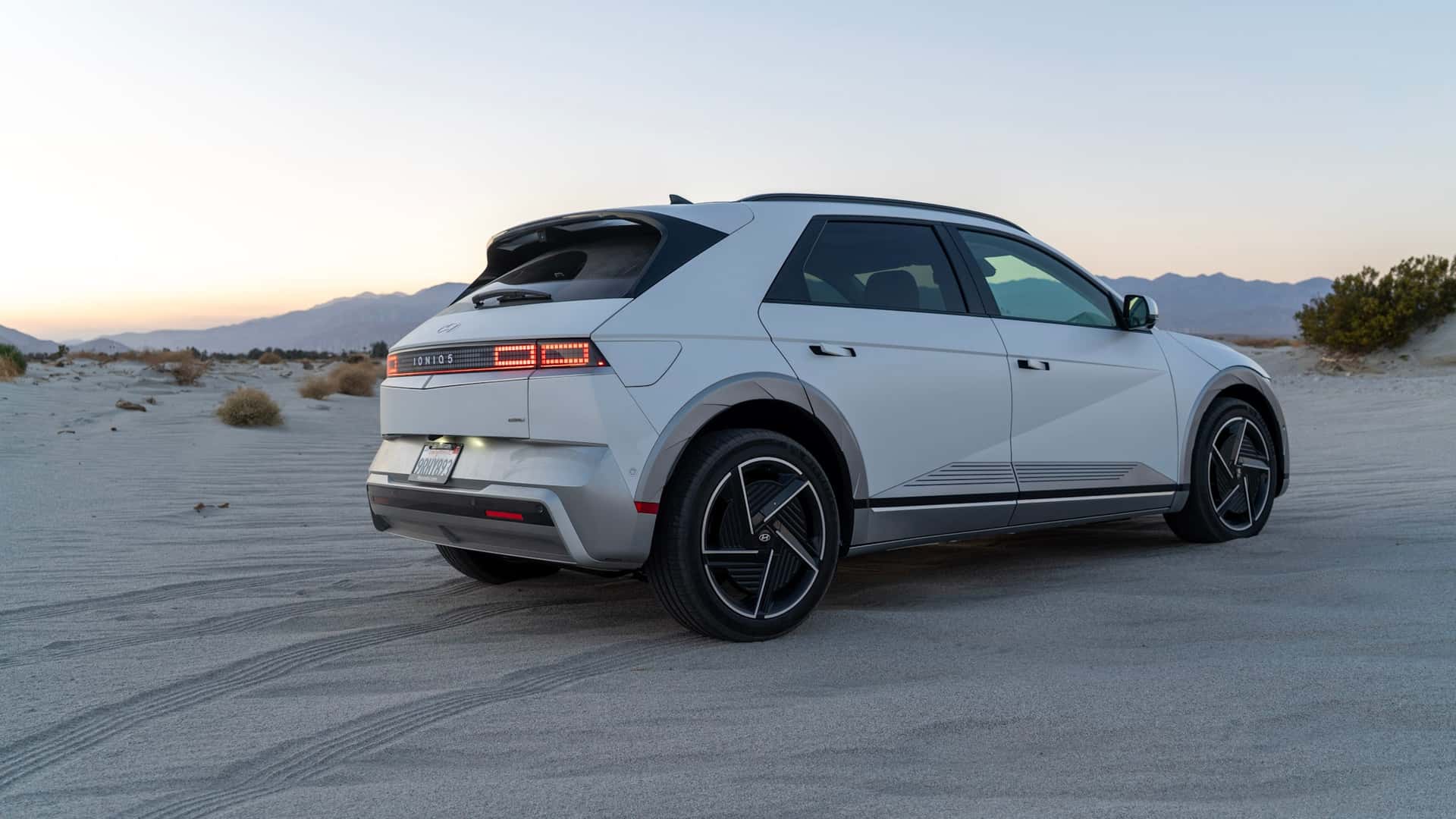 Moderne elbil på sandet ørkenvej ved solnedgang