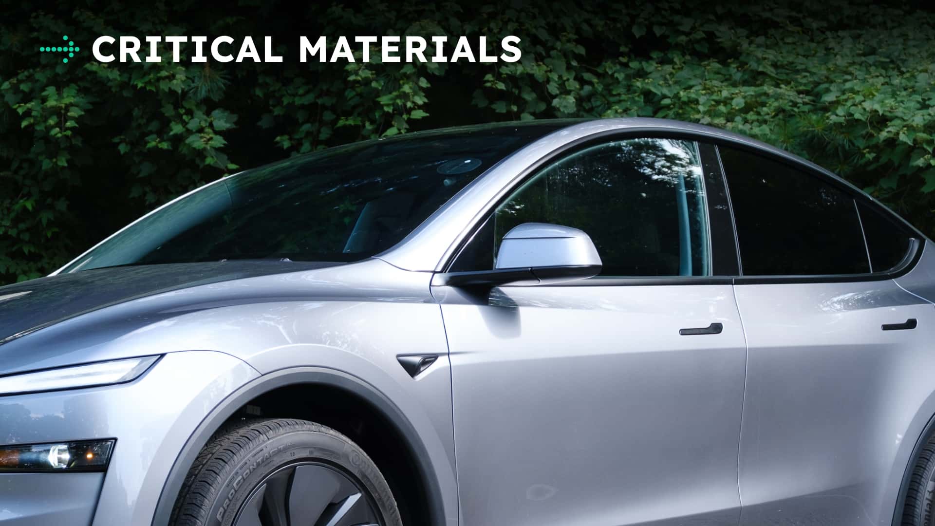 Nærbillede af en Tesla elbil ved skovområde med teksten 'Critical Materials'.