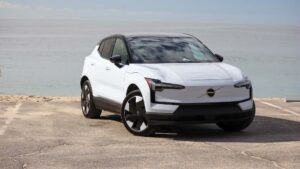 Hvid elektrisk SUV parkeret ved stranden med havudsigt