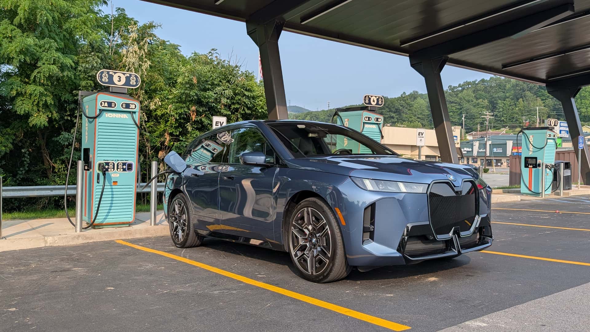 Elektrisk køretøj ved en opladningsstation i grønne omgivelser