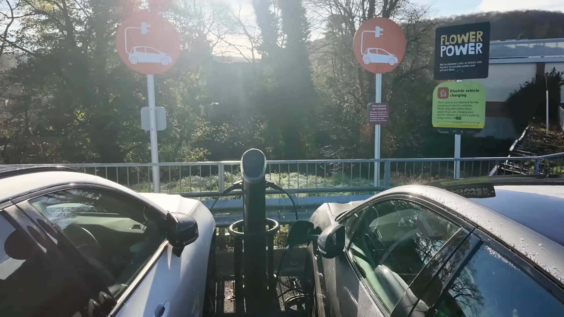 To elbiler til opladning ved en ladestation med Flower Power og opladningsskilte