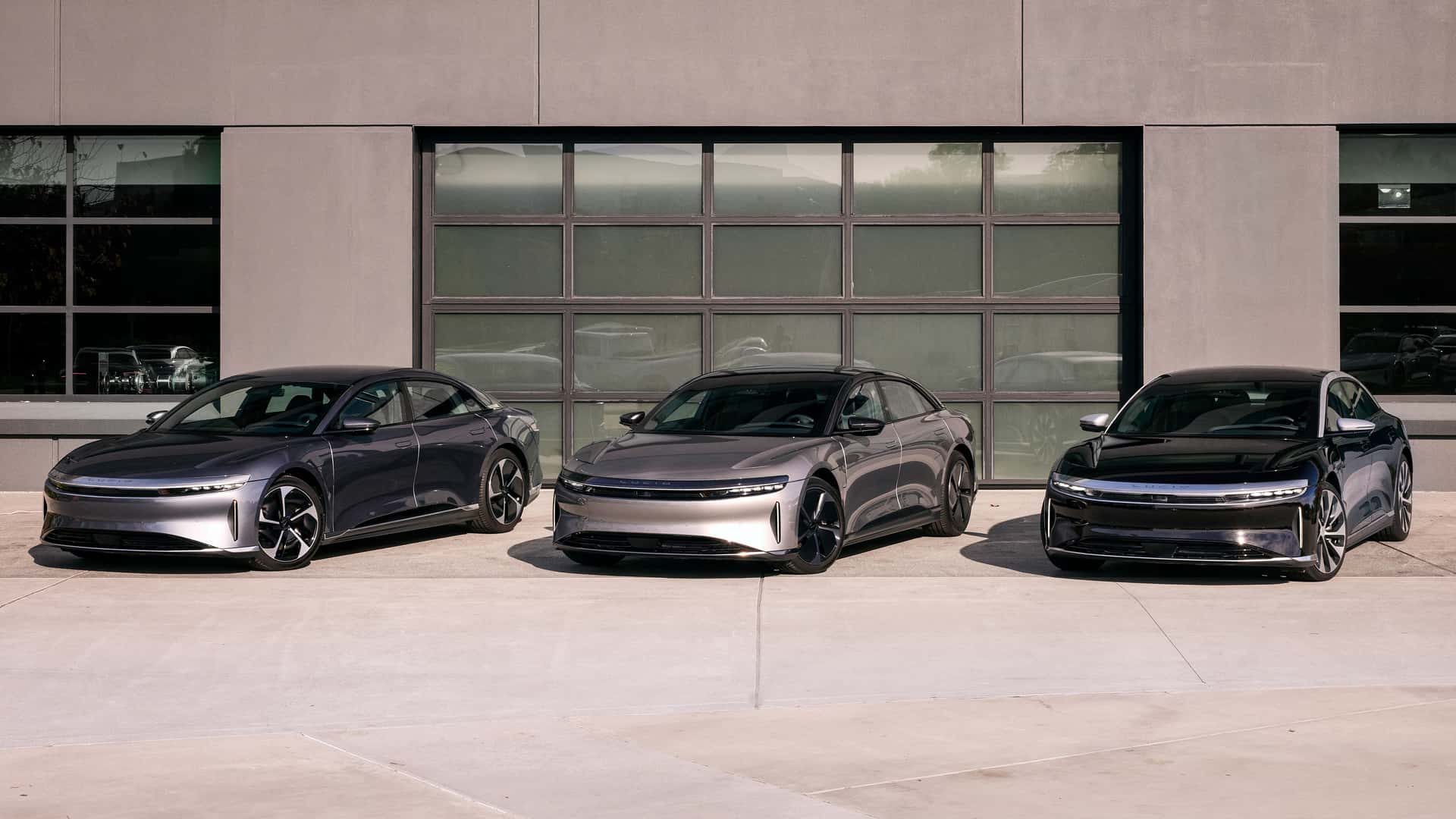 Tre moderne elektriske biler parkeret foran en bygning