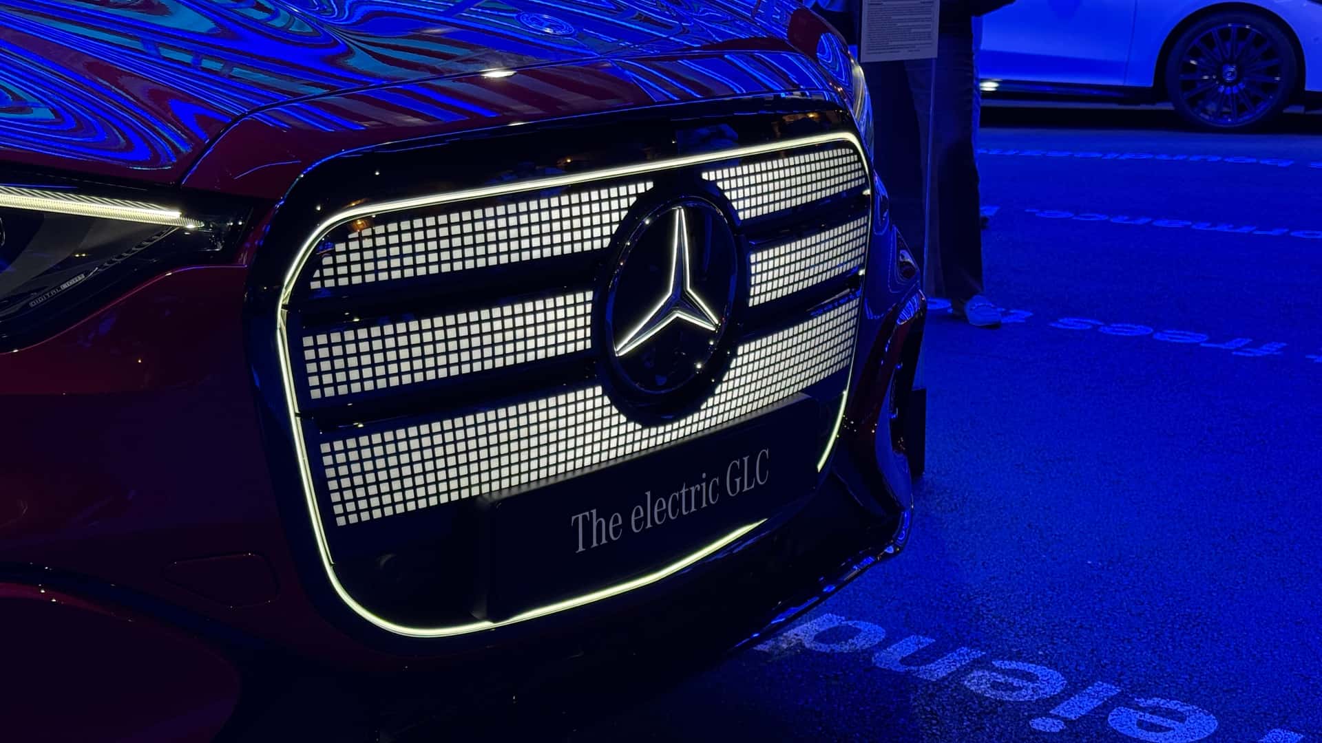 Nærbillede af frontgrillen på en elektrisk Mercedes GLC under blå belysning