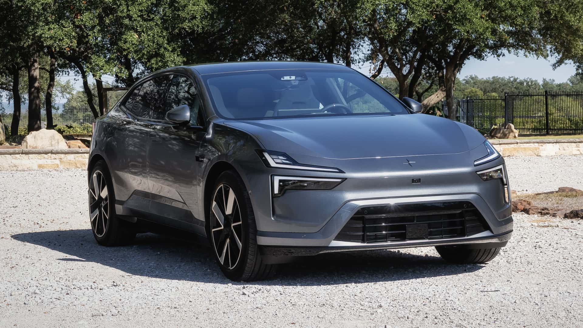 Grå elektrisk bil på en solrig dag foran en række træer