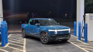 Blå elektrisk pickup truck ved en ladestation om natten