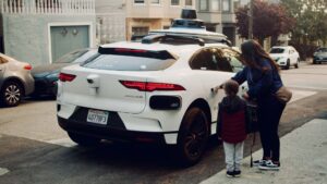 Selvkørende bil fra Waymo holder parkeret på en byvej med en kvinde og et barn ved siden af