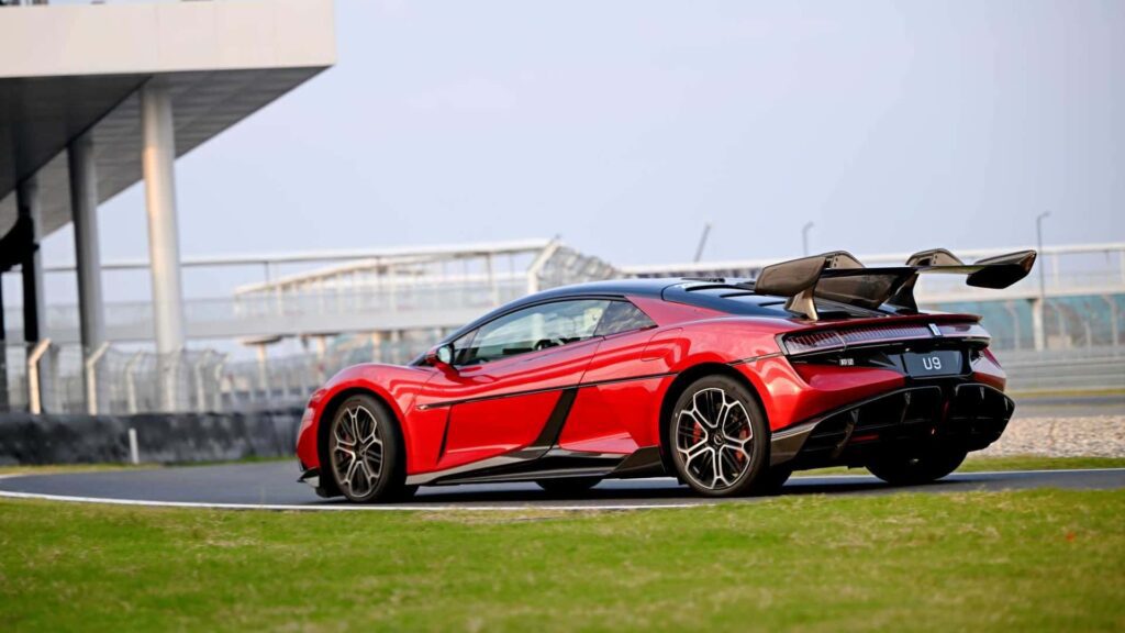 Sportsvogn i rød farve kører på racerbane med stor bagspoiler