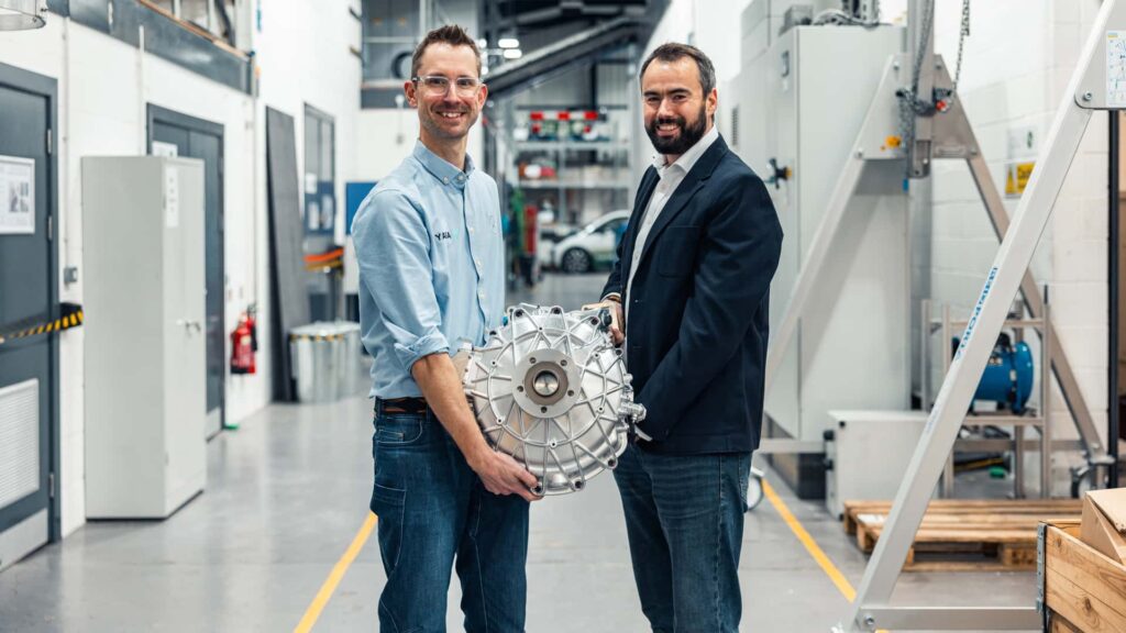 To ingeniører holder en Tesla motor i en industriel bygning