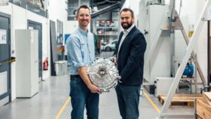 To ingeniører holder en Tesla motor i en industriel bygning