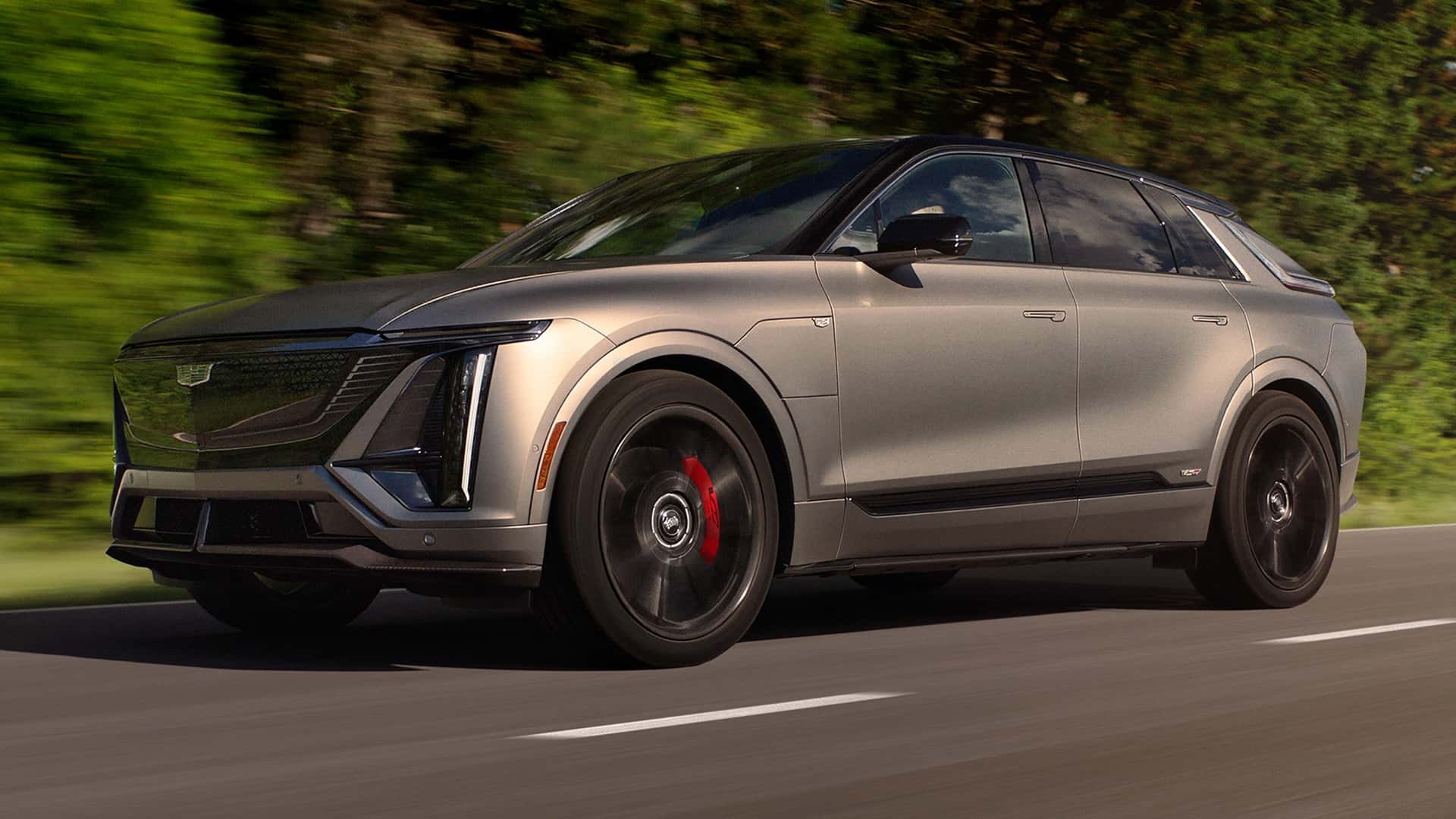 Moderne elektrisk SUV kører på en vej omgivet af grønne træer