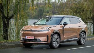 Brun elektrisk SUV parkeret ved en sø på en efterårsdag