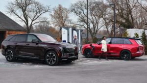 To elektriske SUV'er oplader ved en ladestation i et boligområde.