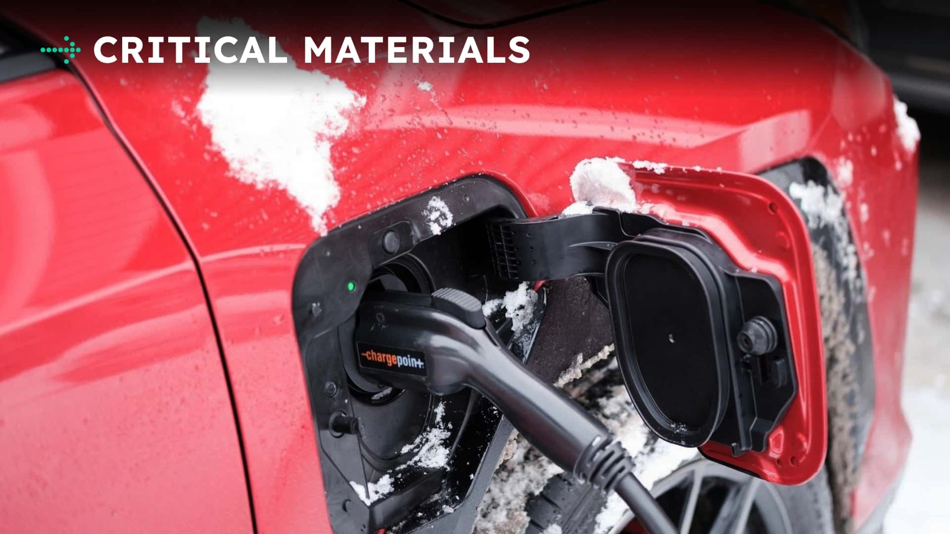 Rød Tesla elbil oplader i snevejr