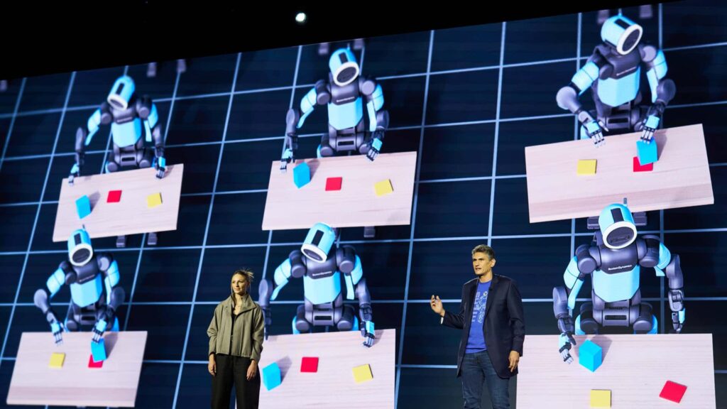 Personer præsenterer robotter, der arbejder ved borde på en skærm