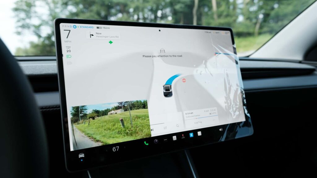 Tesla bilens touchskærm viser navigation og kameravisning under kørsel