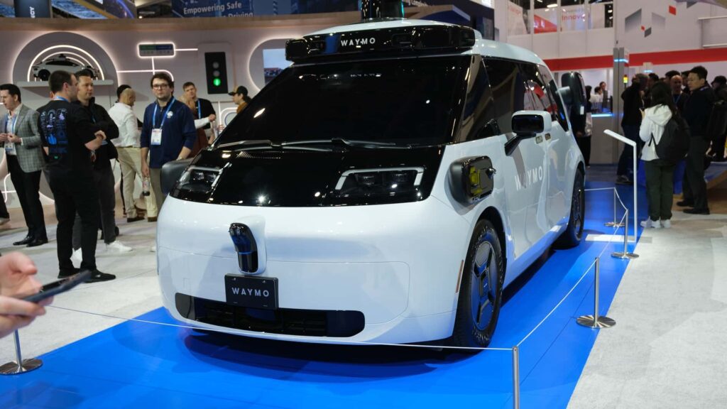 Waymo selvkørende bil udstillet på en messestand med mennesker omkring