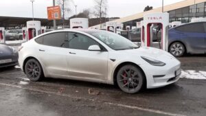Hvid Tesla holder ved en ladestation om vinteren