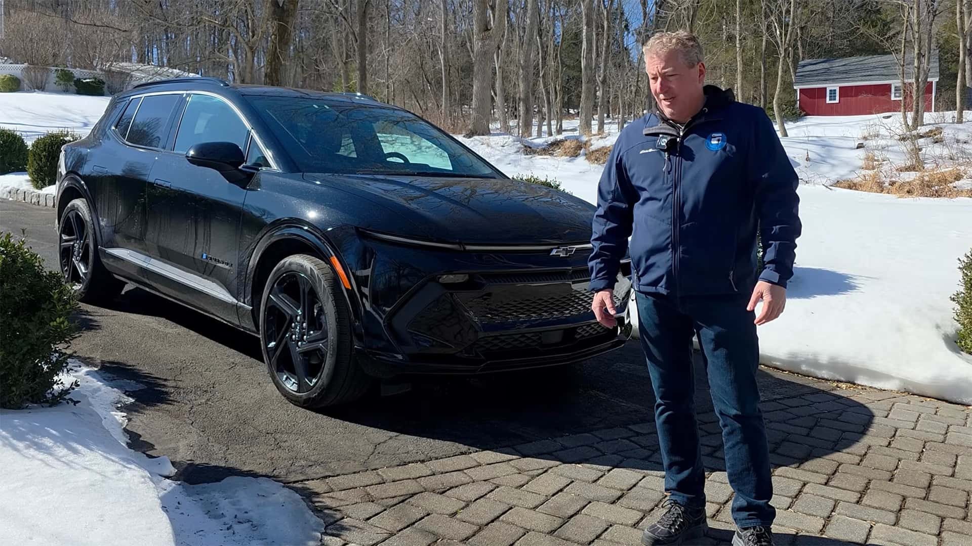 Mand står ved siden af en sort elbil i en vinterlig udendørs scene