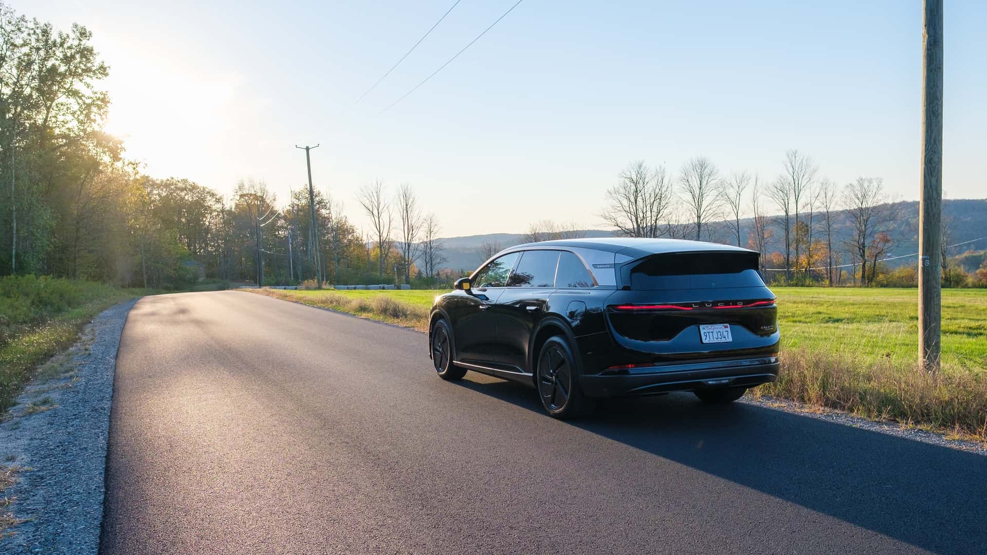 Sort elektrisk bil kører ned ad en landevej om eftermiddagen