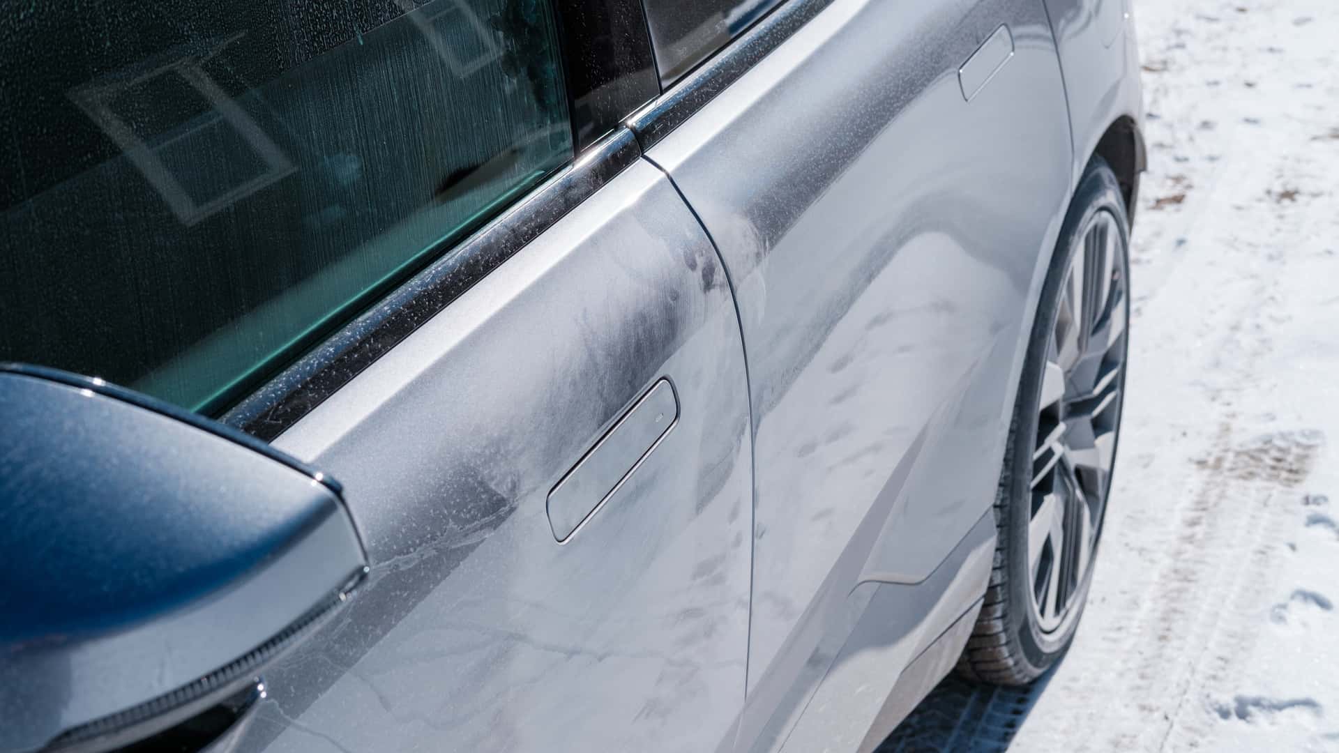 Nærbillede af sidepanelet på en Tesla elbil, der står parkeret i sneen