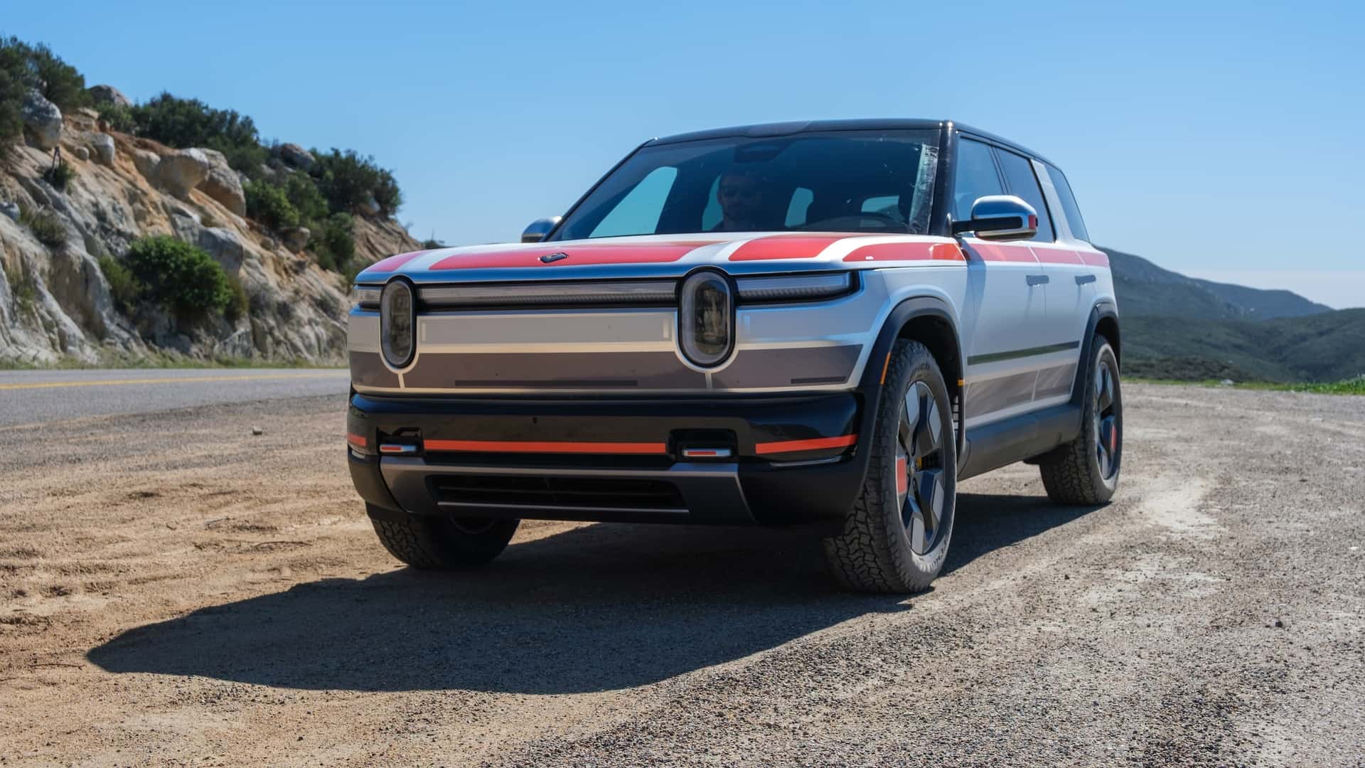 Elektrisk SUV parkeret på en naturskøn landevej under en klar blå himmel