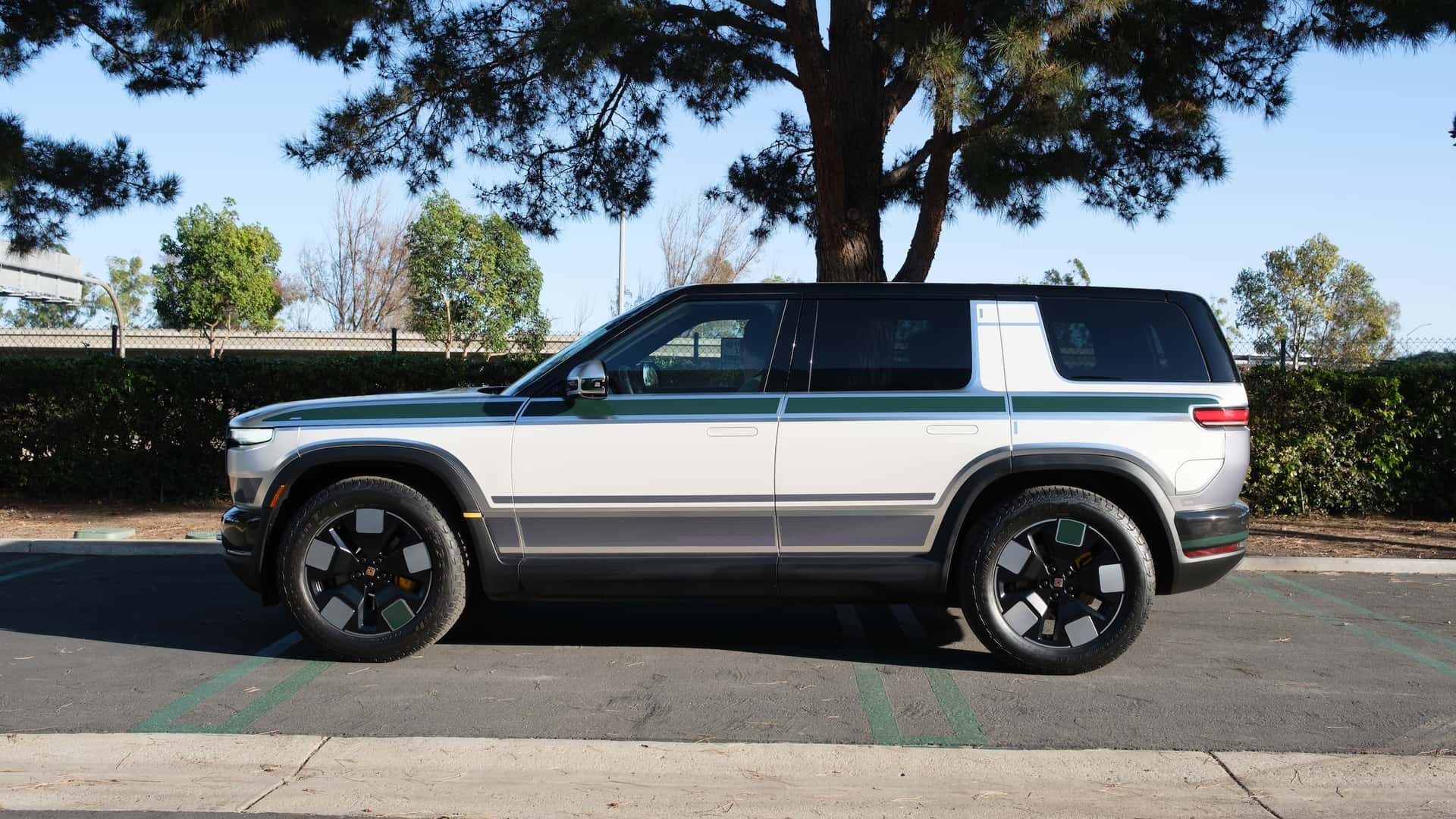 Hvid elbil SUV parkeret ved vejen med træer i baggrunden