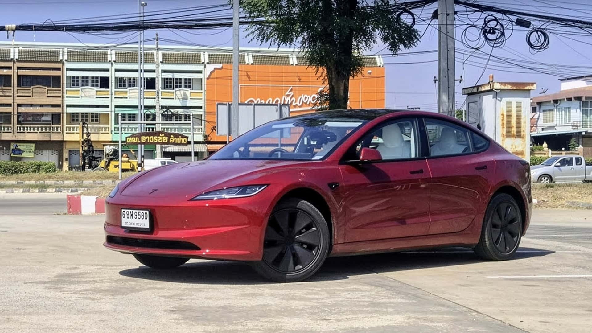 Rød Tesla elbil parkeret udenfor i bymiljø