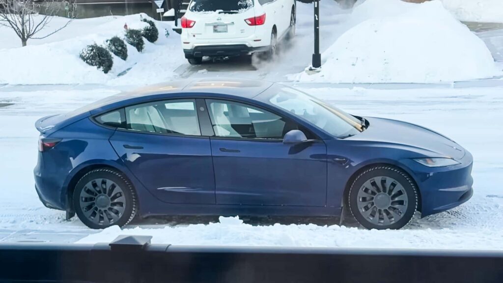 Blå Tesla parkeret i snedækket landskab