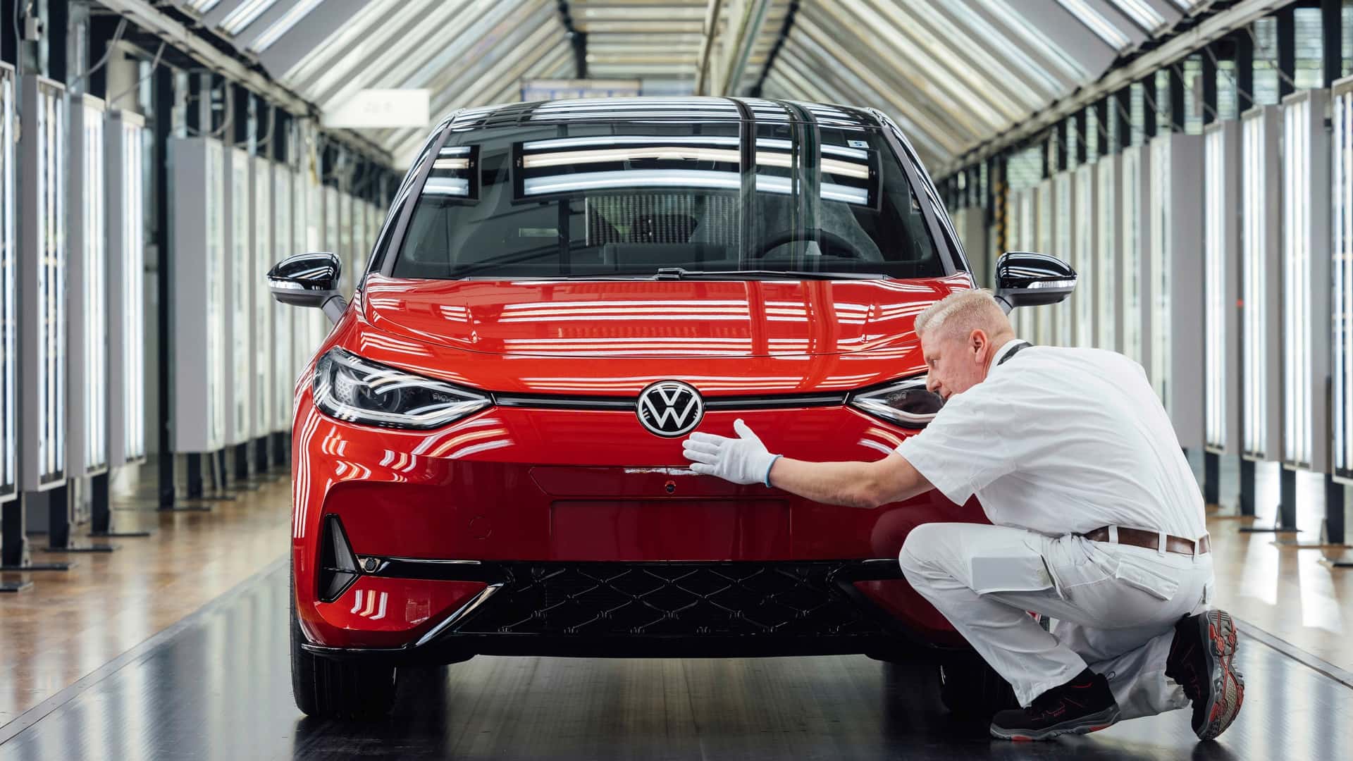 Fabrikarbejder inspicerer en rød elbil i produktionslinjen