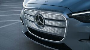 Nærbillede af moderne elbil med futuristisk design og skinnende grill i en parkeringsplads