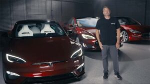 Mand står ved siden af tre Tesla-biler i en garage