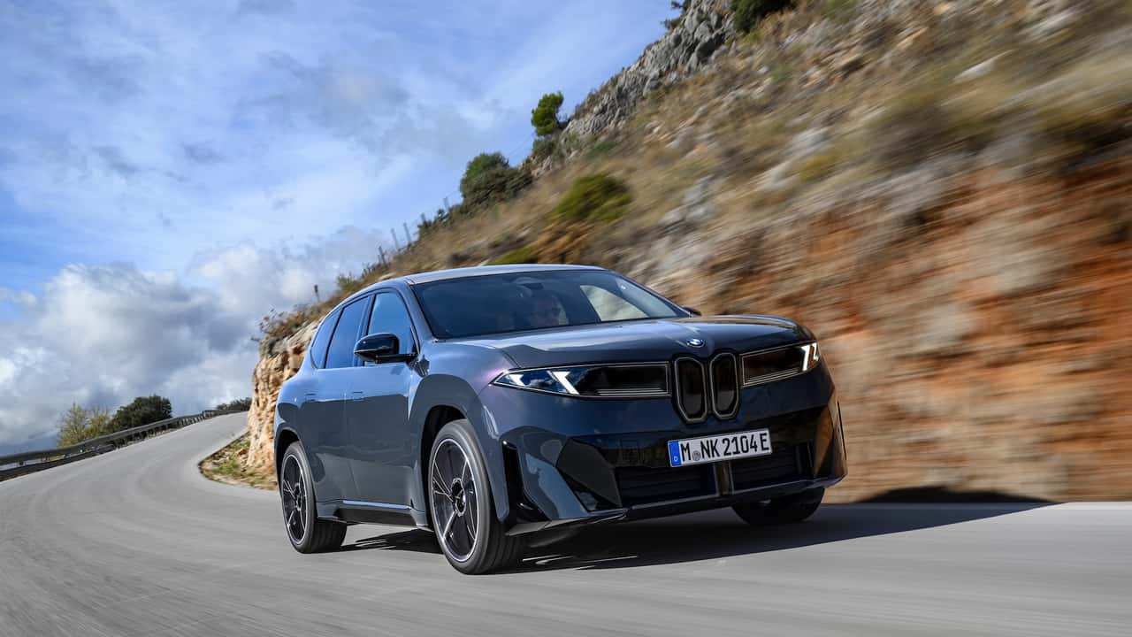 Elektrisk SUV kører langs en naturskøn vej med bjergbaggrund